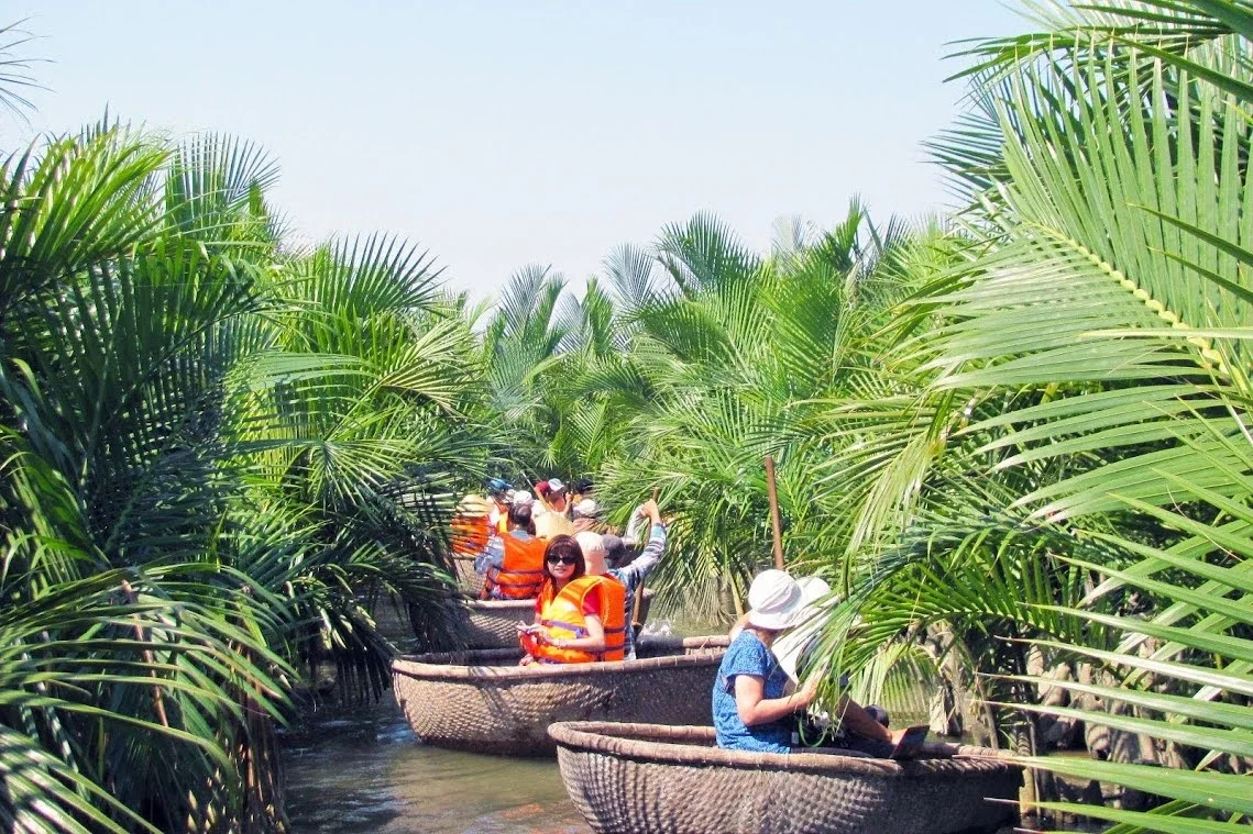 Travelers enjoy a peaceful ride in traditional bamboo basket boats through the water palms of Hoi An on Hoi An basket boat tours.