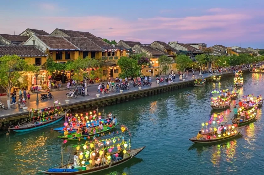 Tourists relaxing on a traditional Hoi An coconut boat tour along the peaceful Do River, a highlight of our eco-luxury trip.