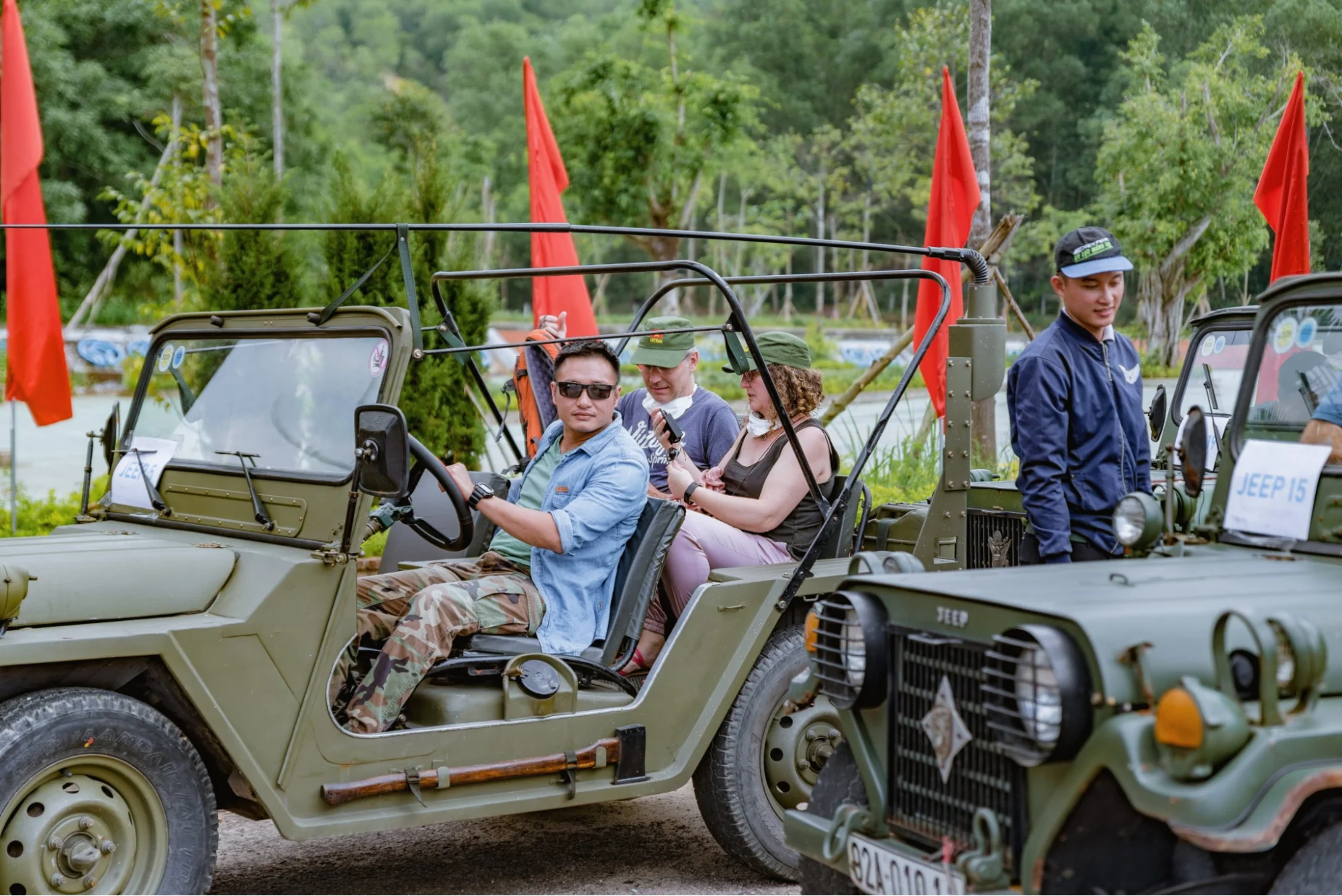 Tourists riding in an open-air vintage Jeep through green rice paddies on a scenic tour to My Son Sanctuary.