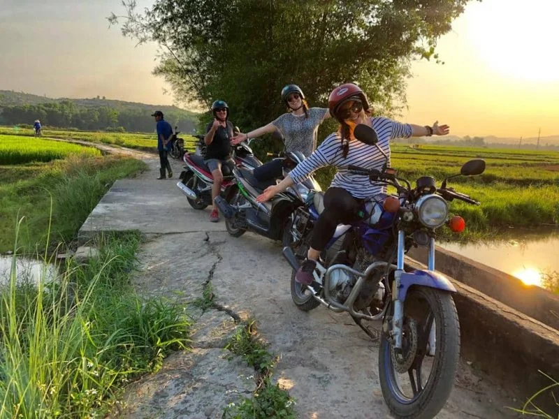 Travelers enjoying a scenic countryside tour Hoi An motorbike experience through the rice fields