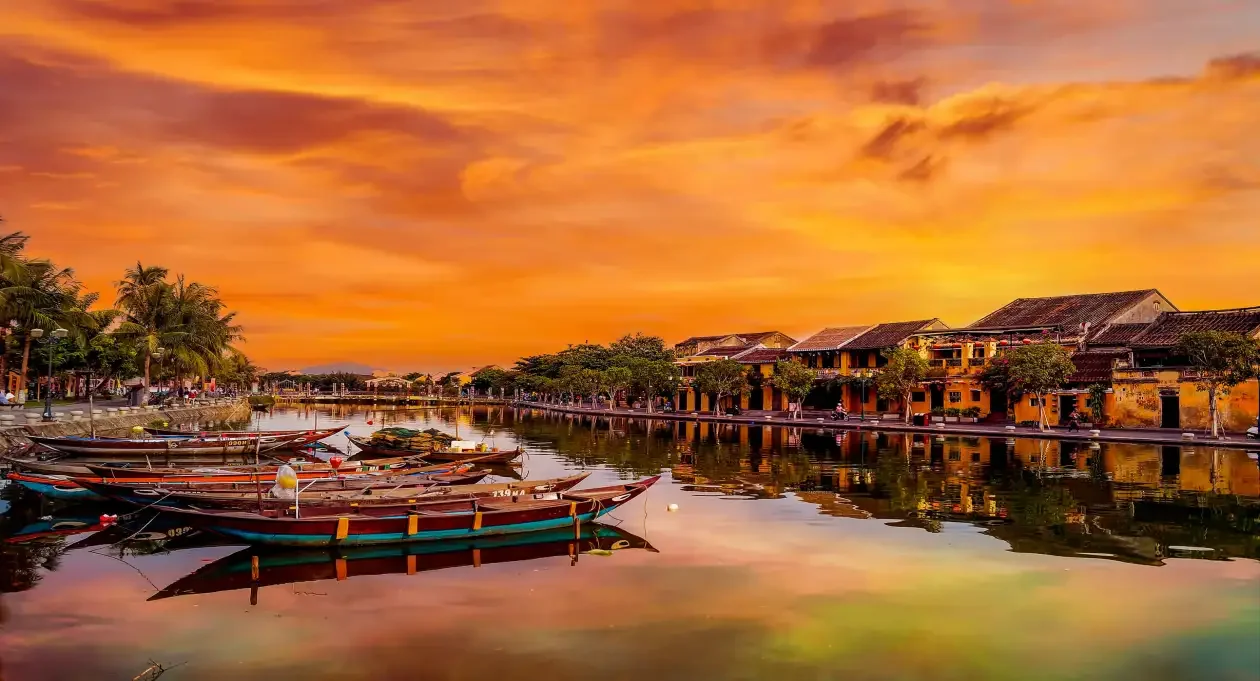 A traditional wooden boat cruising the Thu Bon River during a magical sunset Hoi An.