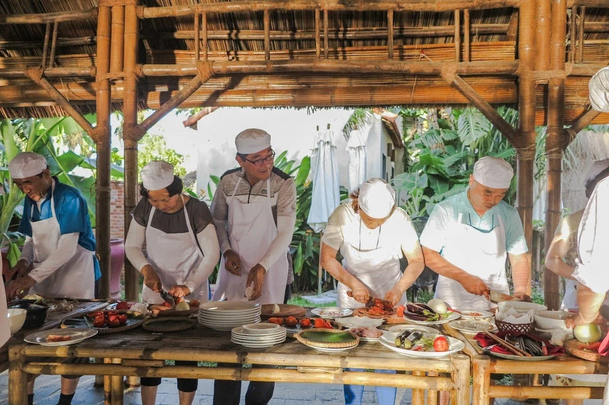 A local host teaching a tourist how to roll fresh spring rolls during a private cooking class in Hoi An.