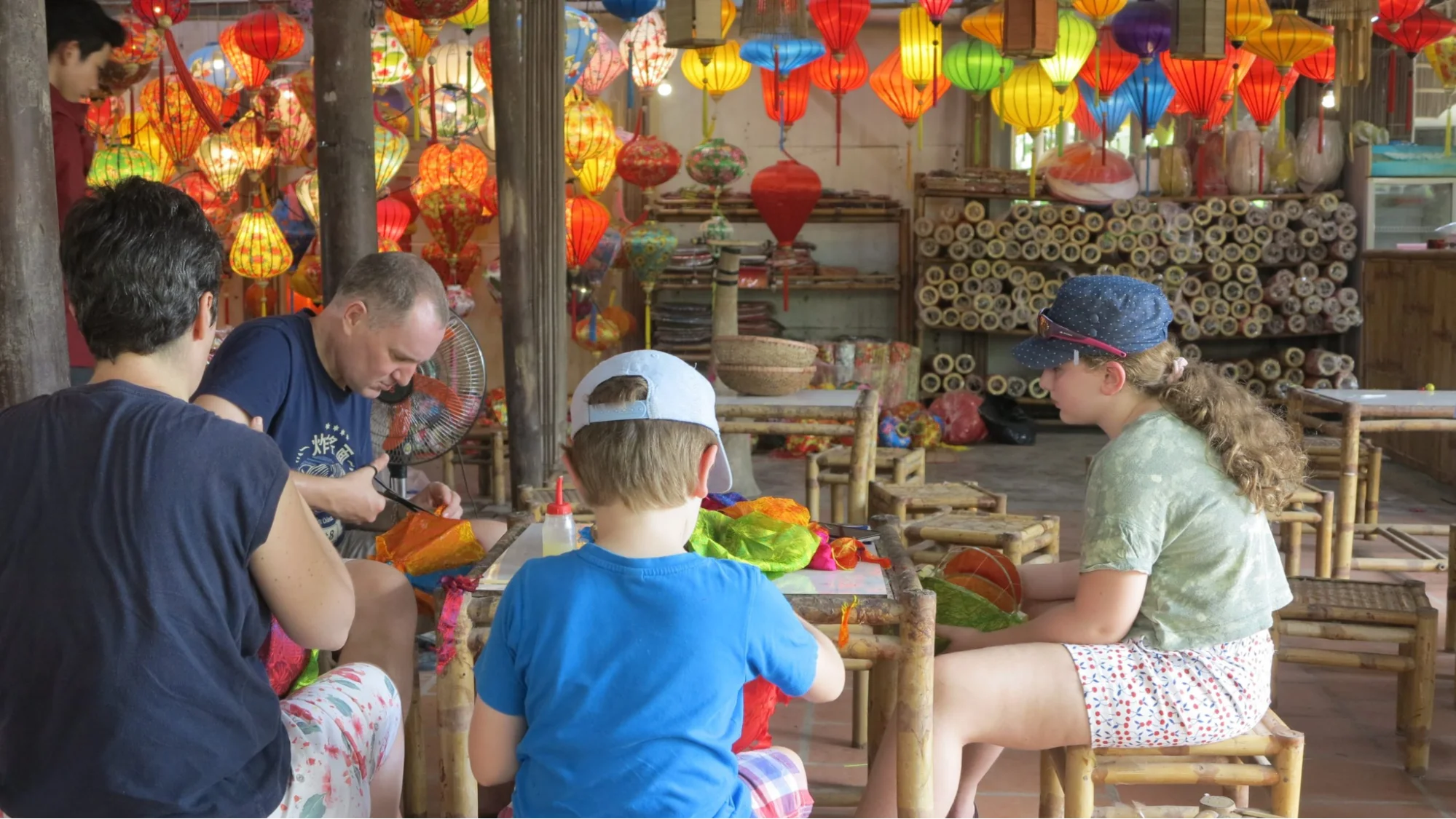 Visitors gluing silk onto a bamboo frame during a Hoi An lantern-making class with a local artisan.