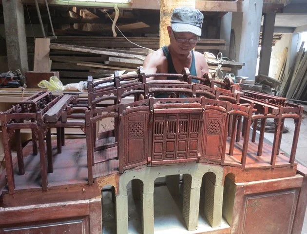 Mr. Huynh Ri is crafting a detailed wooden model during our Vespa tour in Hoi An.