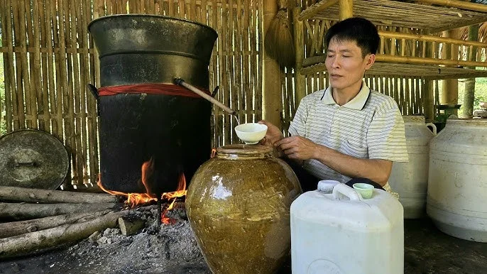 A local villager demonstrating the traditional method of distilling rice wine in a clay pot to tourists.