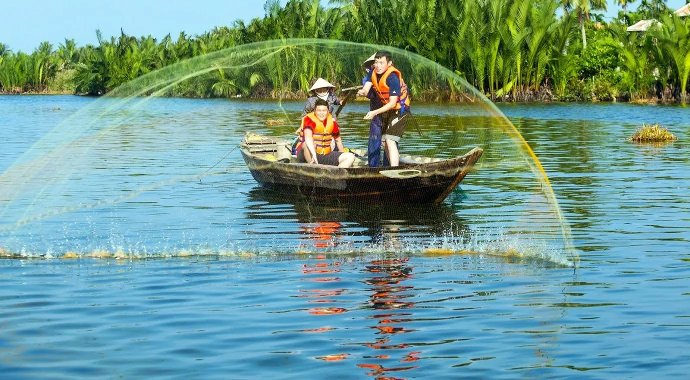 A local fisherman demonstrating how to cast a large fishing net on the river during a farming and fishing tour hoi an
