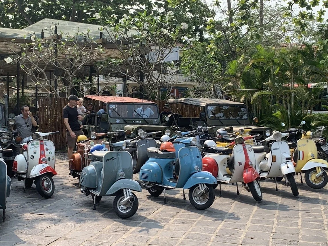 A lineup of colorful vintage scooters parked together before an authentic Hoi An Vespa tour.