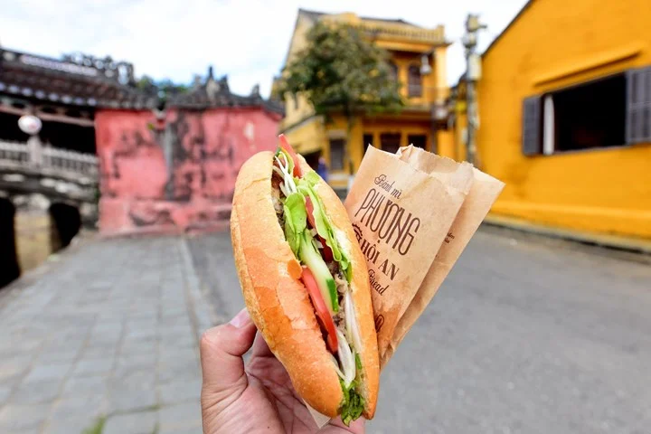 holding a freshly prepared sandwich from banh mi phuong hoi an