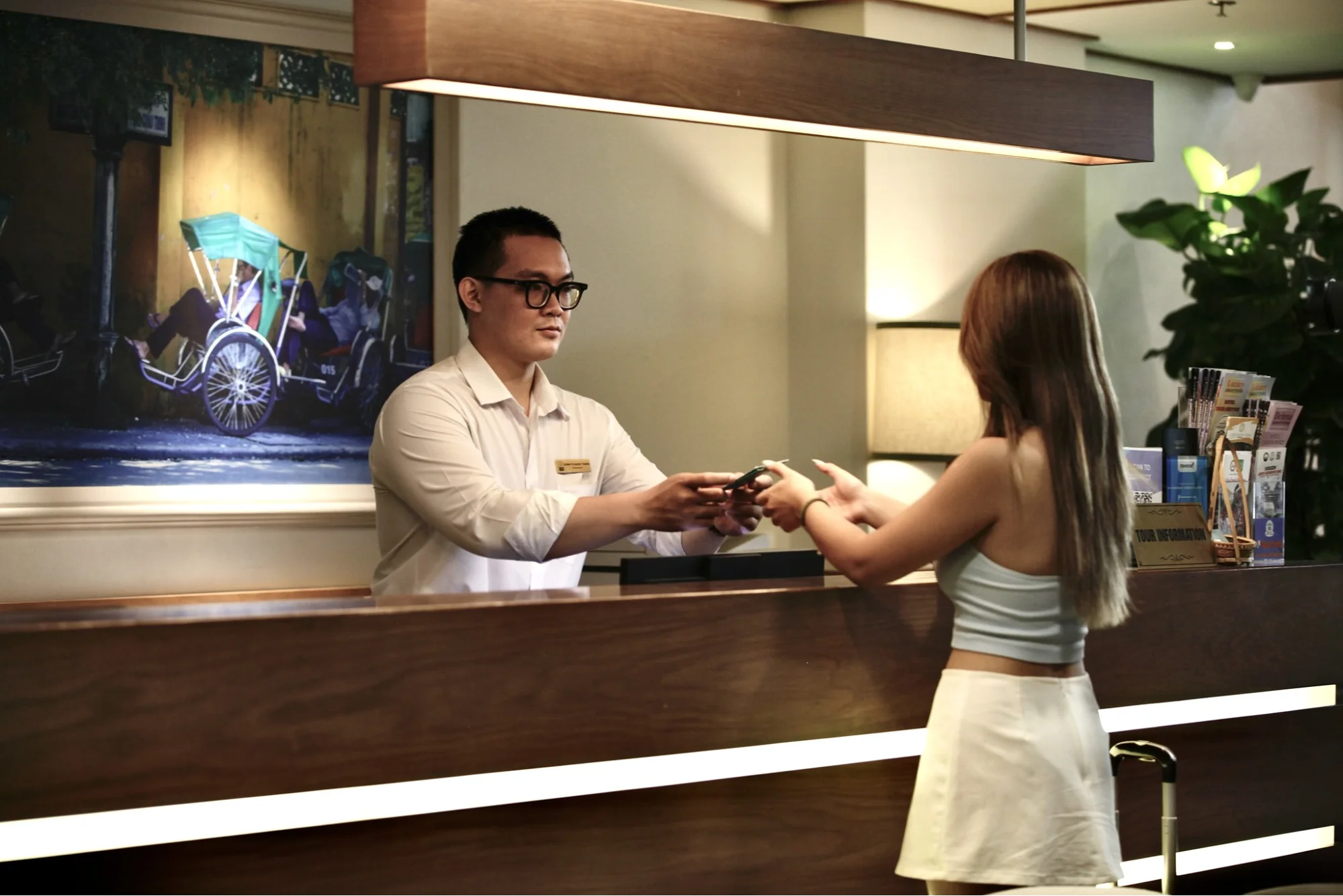 A guest receiving information at a hotel desk, potentially about local attractions like the Bamboo Circus Hoi An.