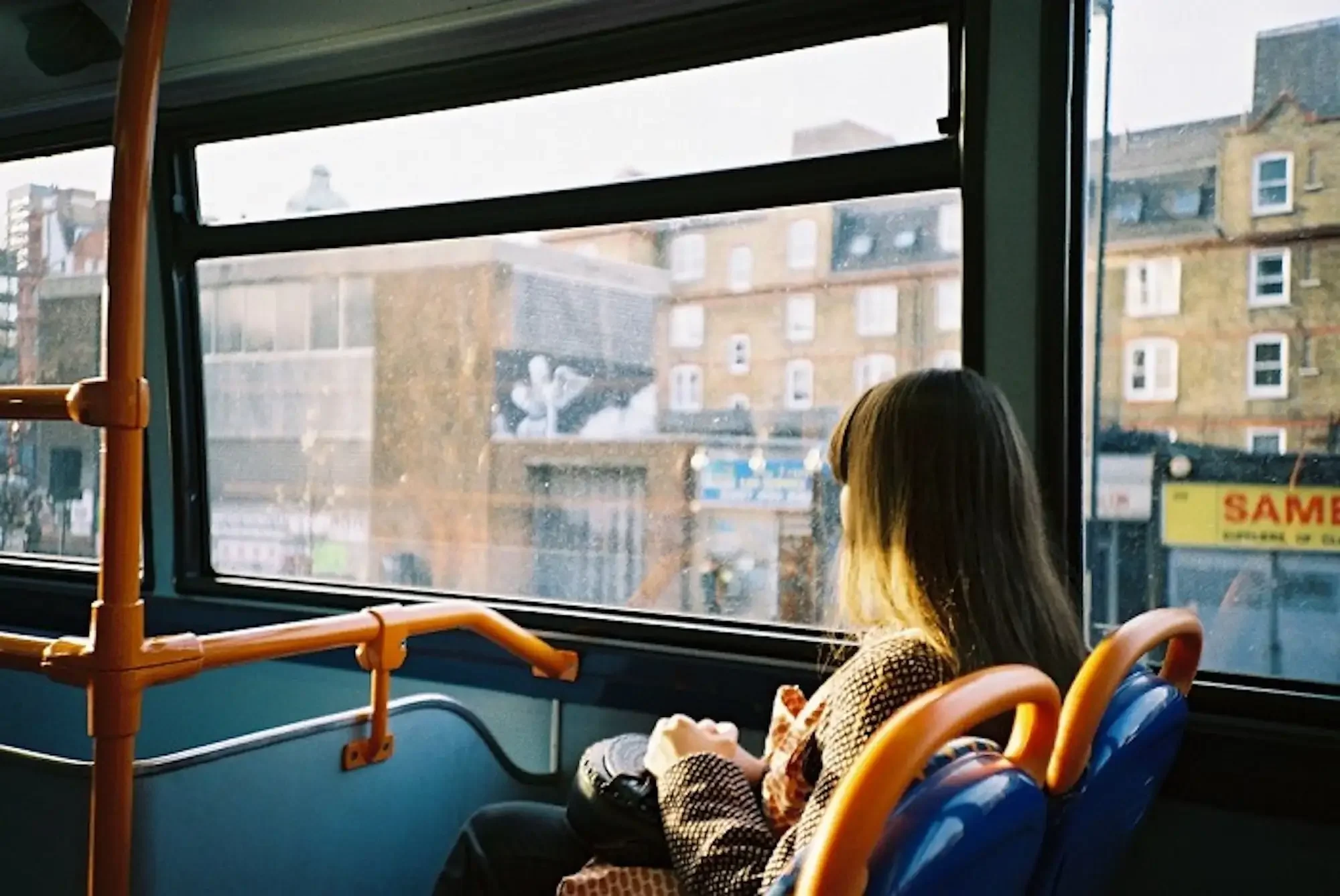 a person riding an electric shuttle bus to the An Bang Beach bus station, looking out the window at urban buildings