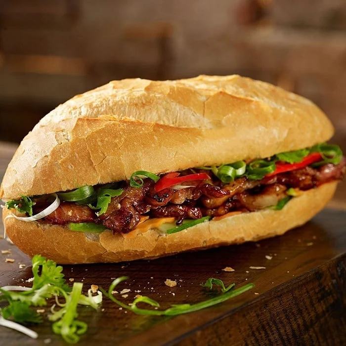 Close-up of a delicious banh mi Hoi An sandwich with grilled pork and fresh herbs