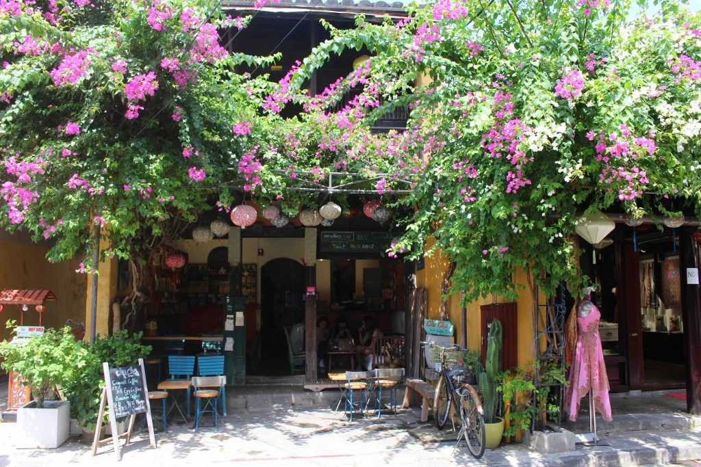 Charming cafe entrance draped in bougainvillea, a popular spot for specialty coffee Hoi An.