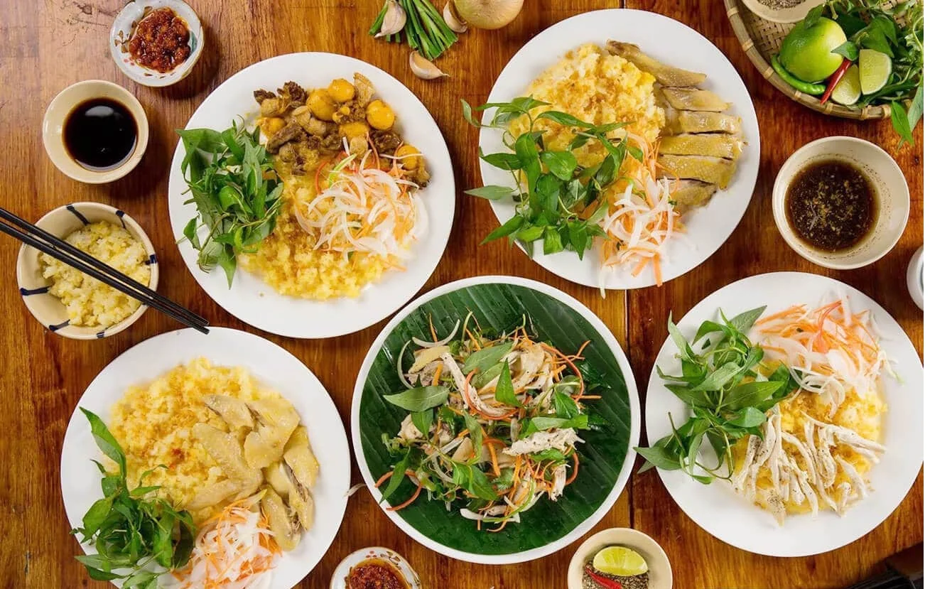 Plates of Hoi An chicken rice served with herbs and dipping sauce.