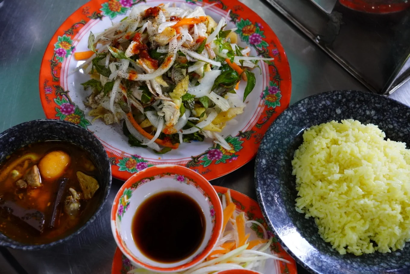 A plate of Hoi An chicken rice with shredded chicken salad and pickled vegetables.