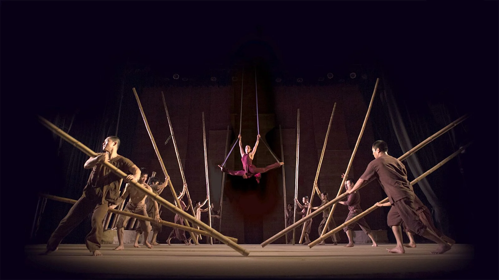 Acrobats performing with bamboo poles and an aerialist suspended on silks at the Bamboo Circus Hoi An.