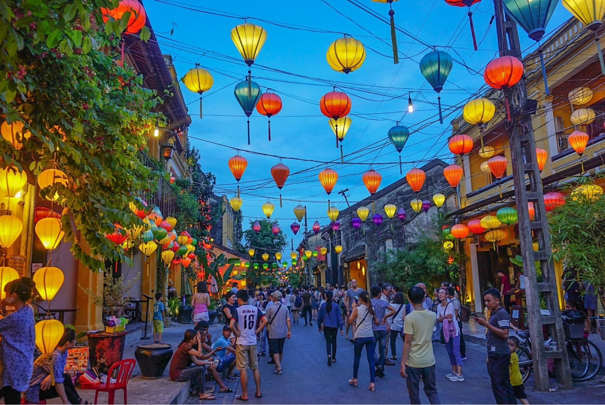 People walking under colorful lanterns during the Hoi An Lantern Festival