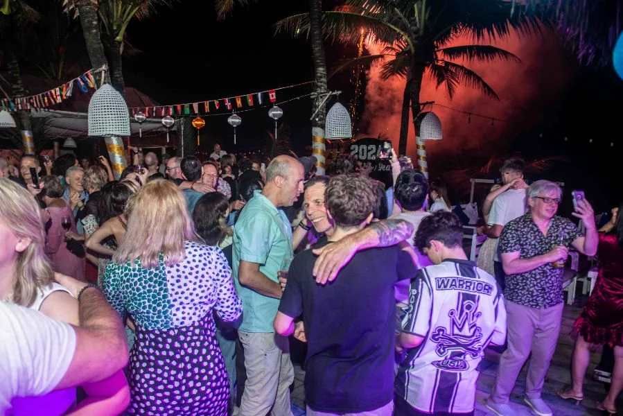 people celebrating new year at a lively beach party at An Bang Beach at night with festive lights