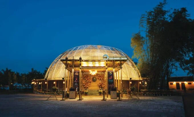 The illuminated bamboo dome venue and entrance of the Bamboo Circus Hoi An at twilight.