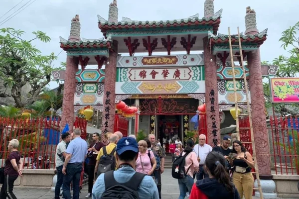 Tourists gather in front of the ornate entrance gate of the Cantonese Assembly Hall Hoi An, featuring traditional Chinese architecture and decorations.