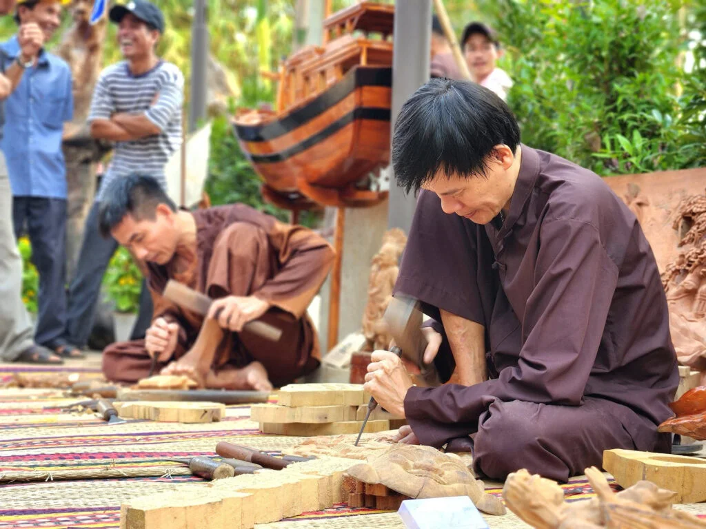 Artisans meticulously carving wooden pieces in a workshop at Kim Bong Carpentry Village Hoi An.