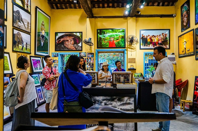visitors exploring the vibrant collection of photographs at the Precious Heritage Art Gallery Museum in Hoi An.