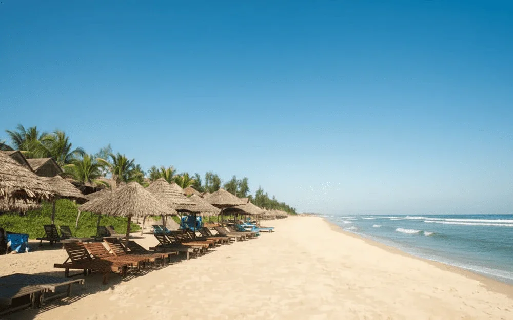 A beautiful sandy beach with umbrellas and lounge chairs, one of the relaxing things to do in Hoi An.