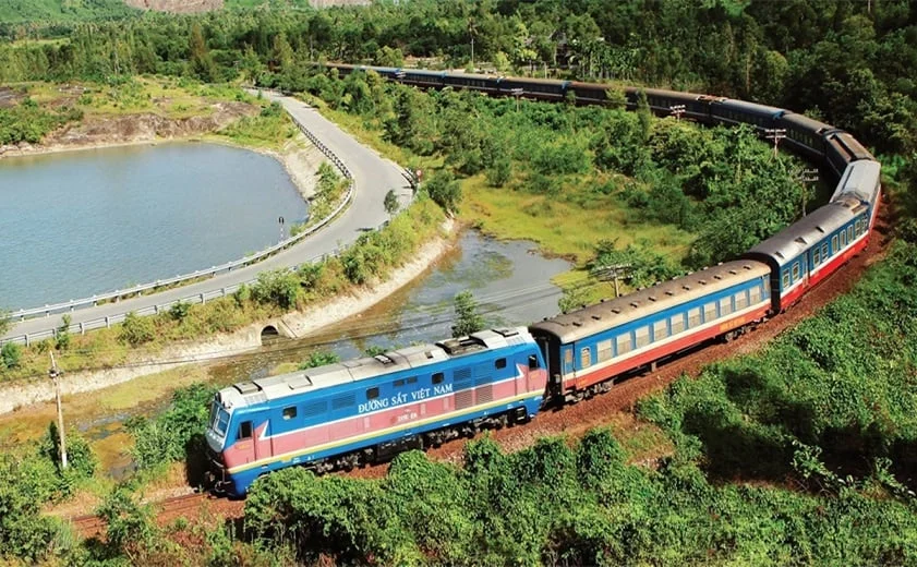 a scenic train ride winding through lush mountains and a lake, a travel option when comparing Hoi An vs Hue for your trip.