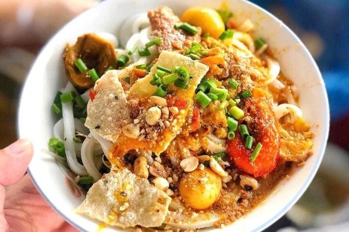 a vibrant bowl of mi quang, a signature noodle dish from Da Nang, representing the culinary battle in Da Nang vs Hoi An