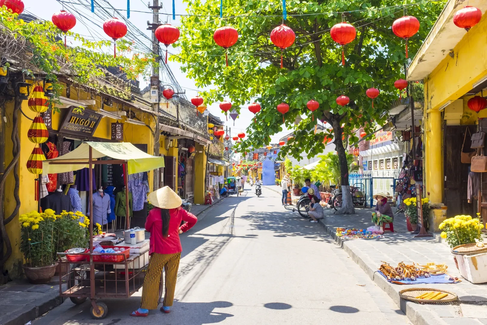 A street scene with yellow buildings and red lanterns, one of the top things to do in Hoi An Ancient Town.