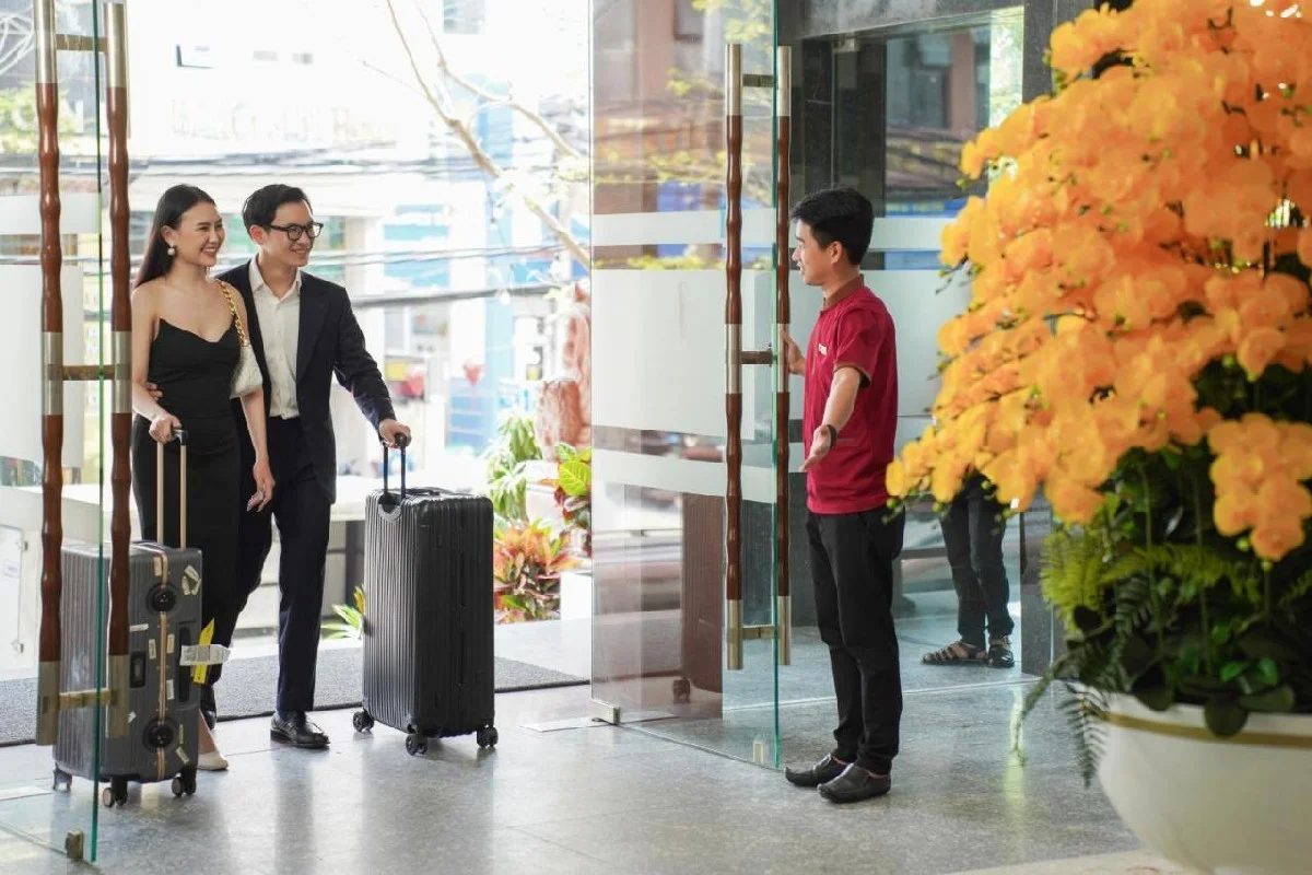 a smiling couple with luggage checking into their hotel, a perfect base for a day trip to Hoi An from Da Nang.