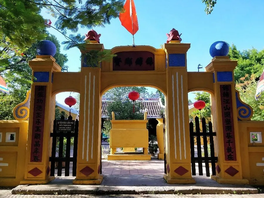 Yellow entrance gate of Cam Pho Communal House under bright daytime sunlight.