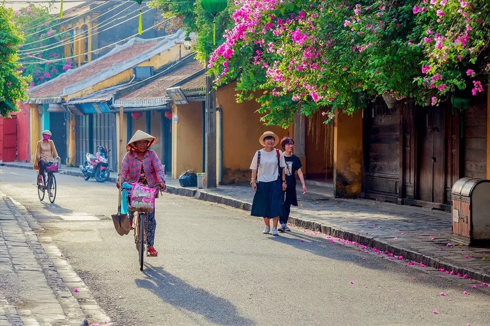 Woman riding a bicycle on a quiet Hoi An street near Cam Pho communal house