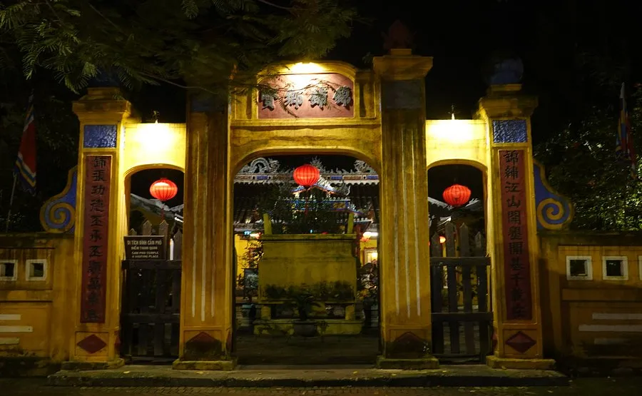 Illuminated three-door entrance gate of Cam Pho Communal House at night.