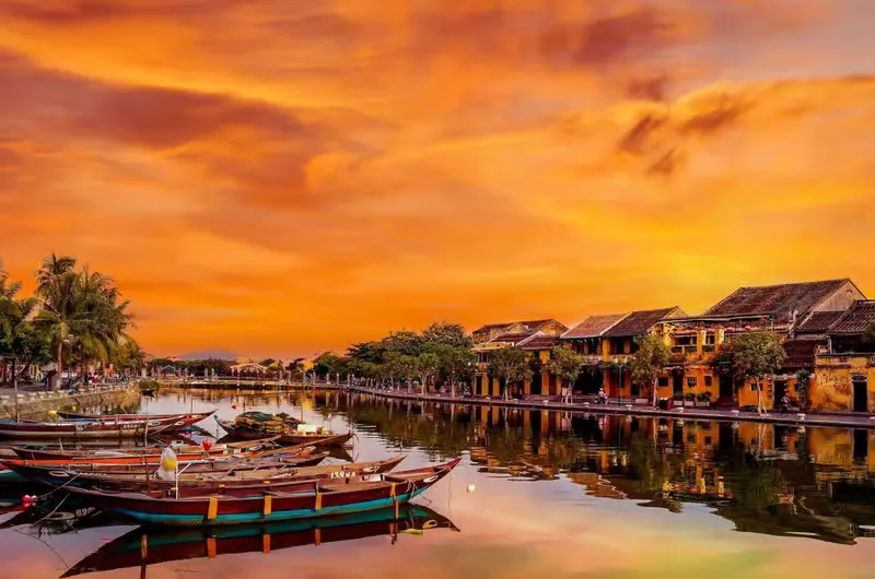 Wooden boats moored at sunset reflecting heritage buildings near Cam Nam Island.