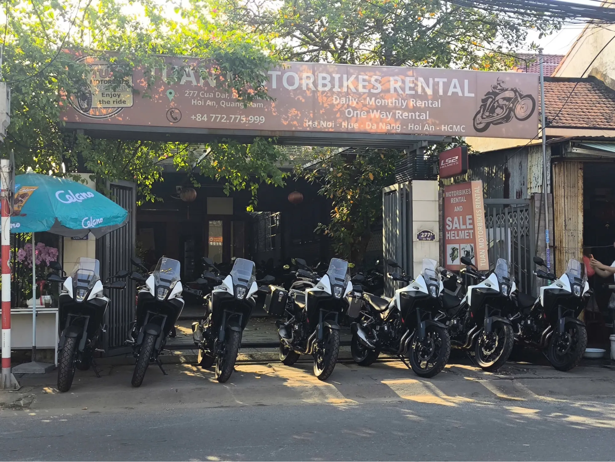 A row of motorbikes parked outside the Tuan Motorbike Rental Hoi An shop.