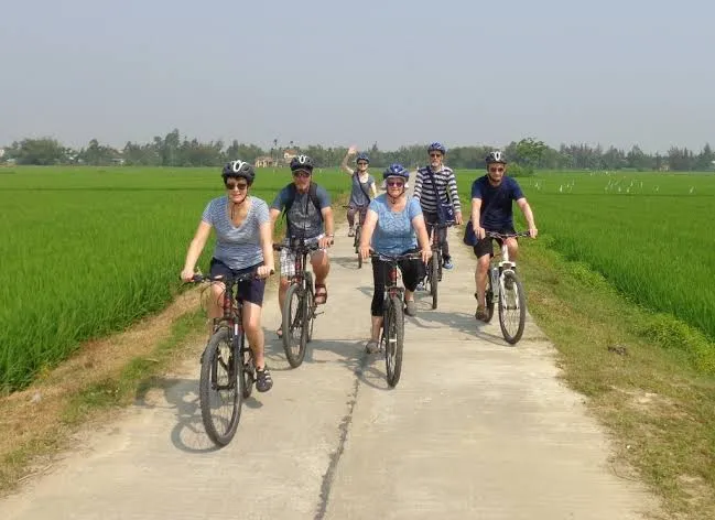 Group enjoying a bicycle rental Hoi An ride through lush rice paddies.