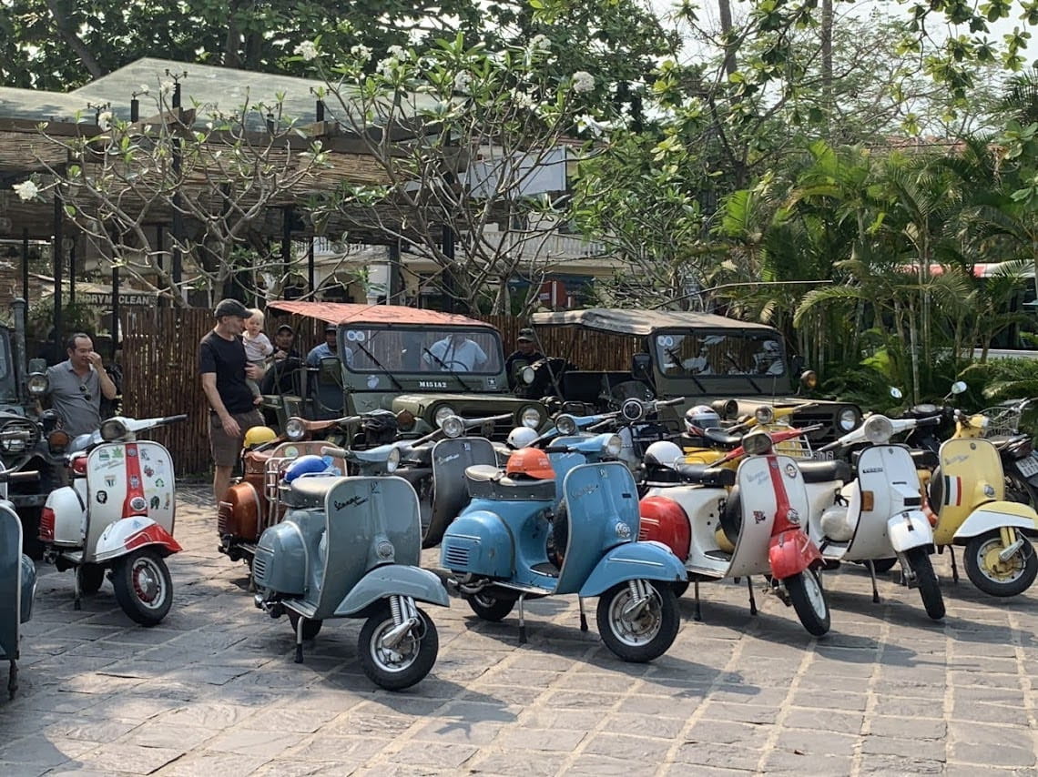 Tourist riding pillion on a vintage Vespa tour through Cam Kim Island in Hoi An