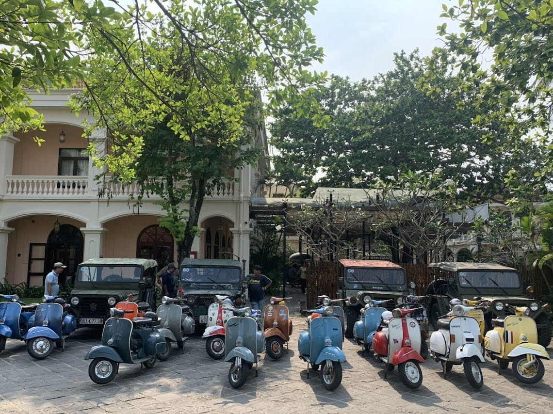 A collection of classic vintage Vespas and military jeeps prepared for a countryside jeep excursion from Hoi An.