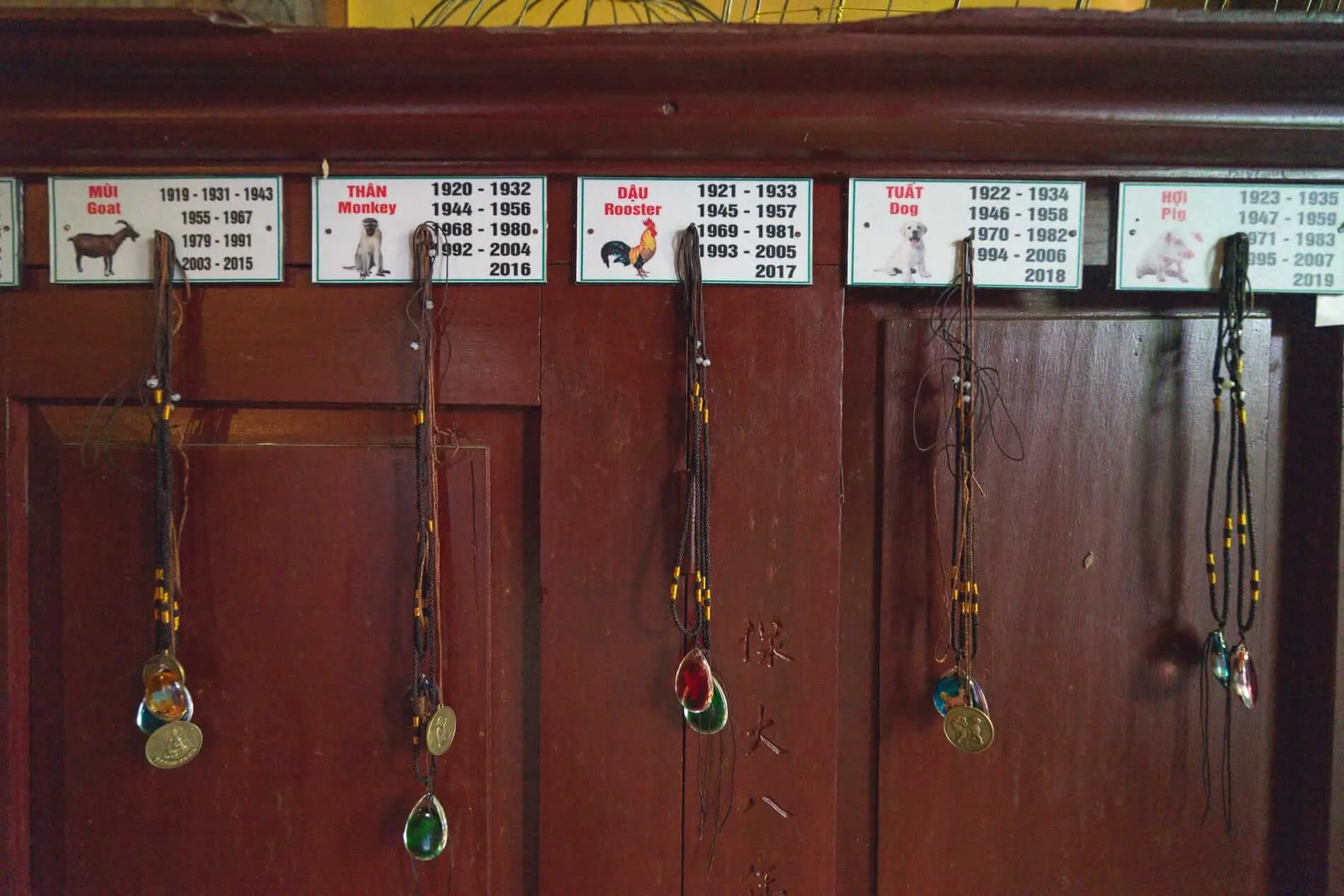 Wooden cabinet displaying zodiac amulets and birth years at Quan Am Pagoda Hoi An.