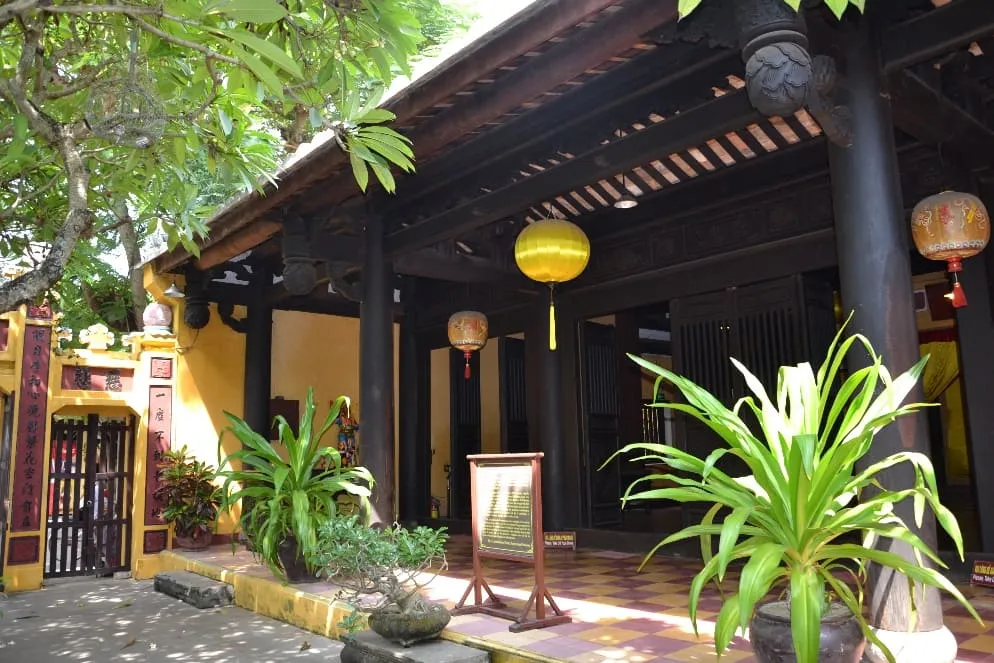 Traditional courtyard at Quan Am Pagoda Hoi An featuring wooden pillars and silk lanterns.