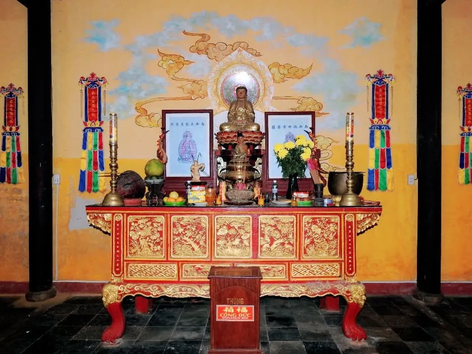 Ornate red altar and Buddha statues inside Quan Am Pagoda Hoi An.