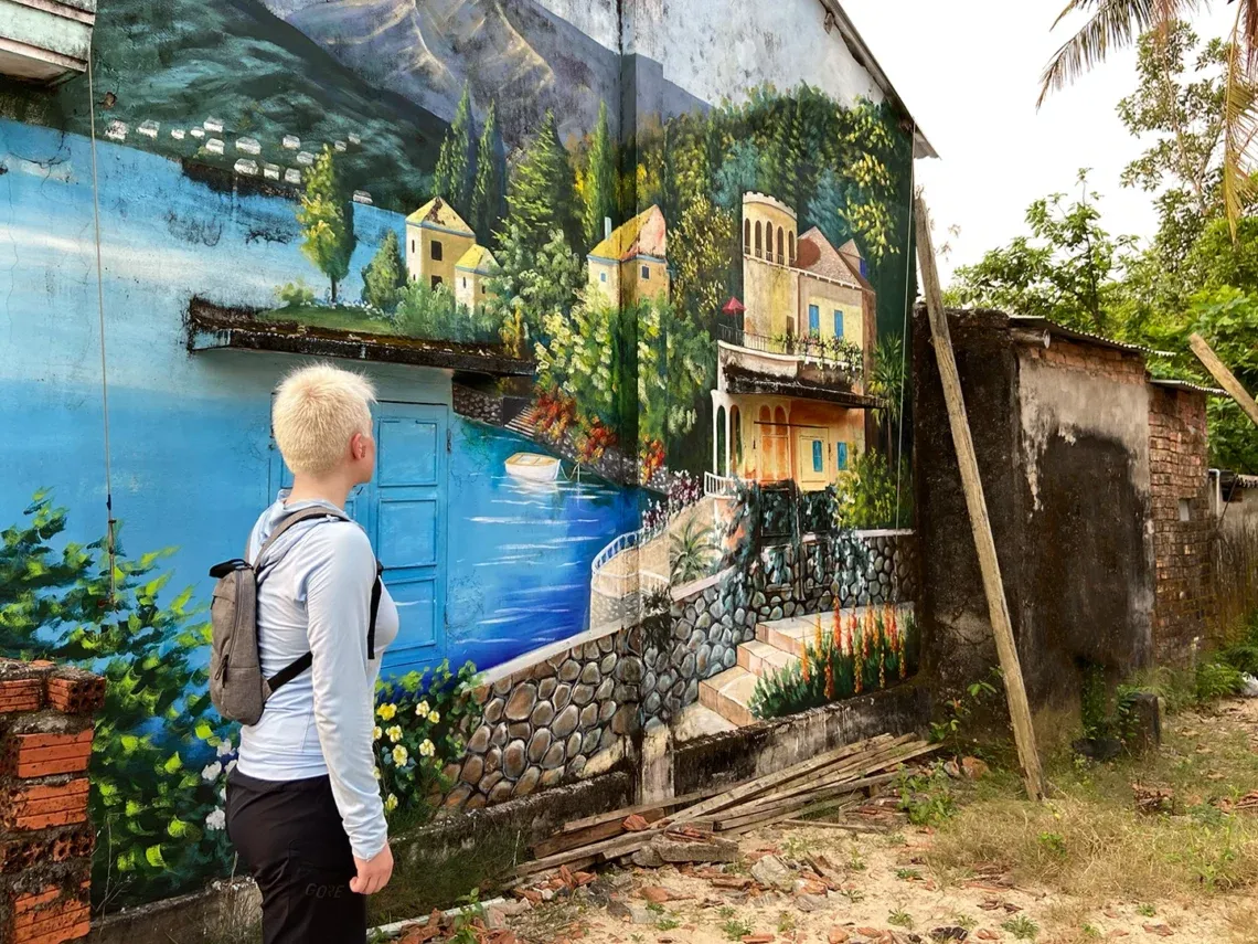 Tourist looking at a landscape painting on a house in Tam Thanh Mural Village.