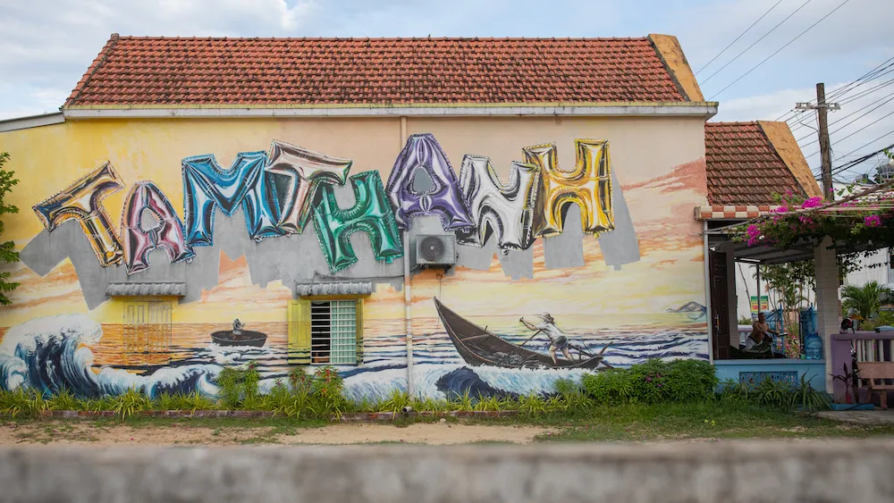 Large coastal mural with balloon letters on a house in Tam Thanh Mural Village.
