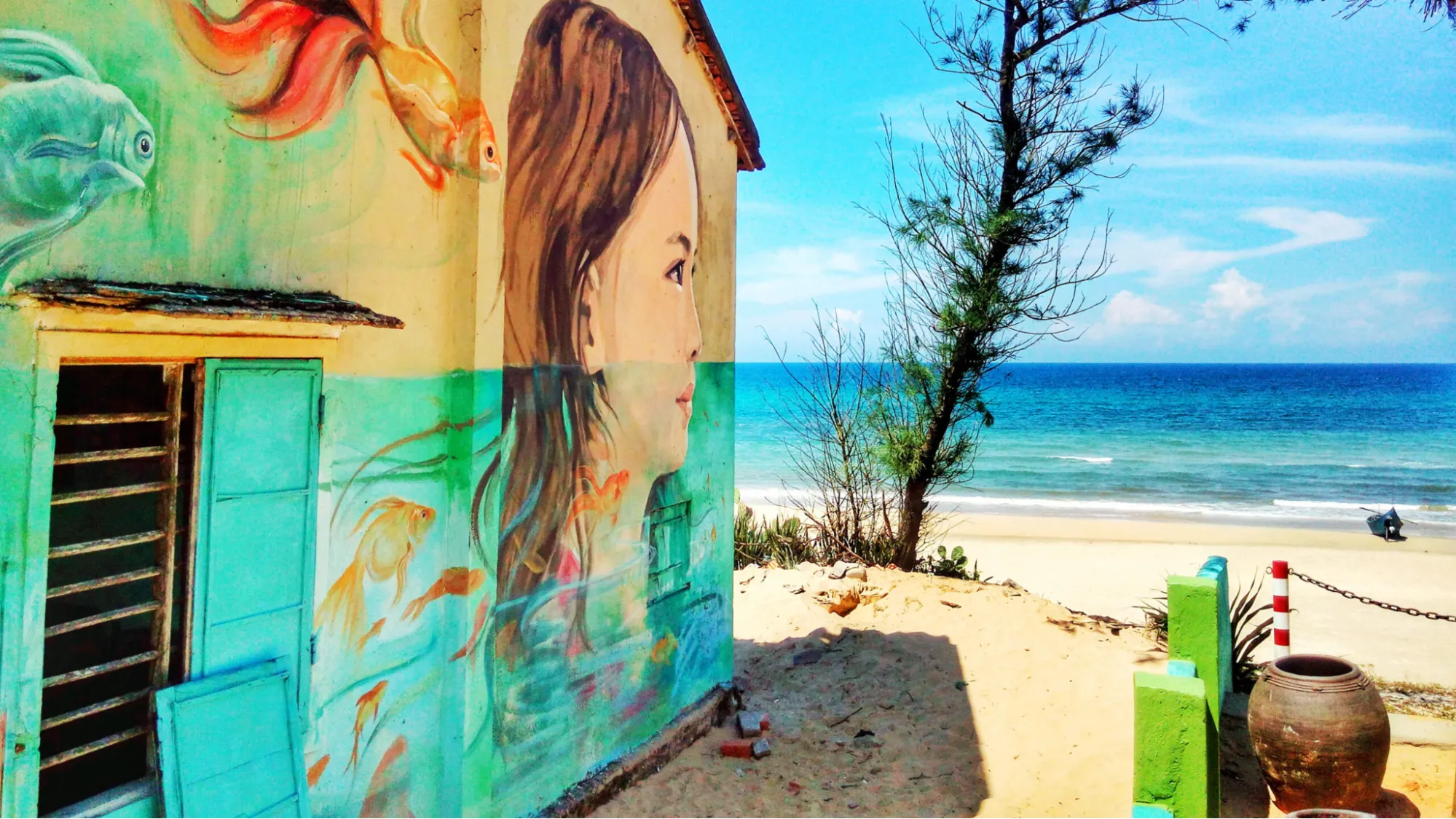 Mural of a girl and goldfish on a beachfront house in Tam Thanh Mural Village.