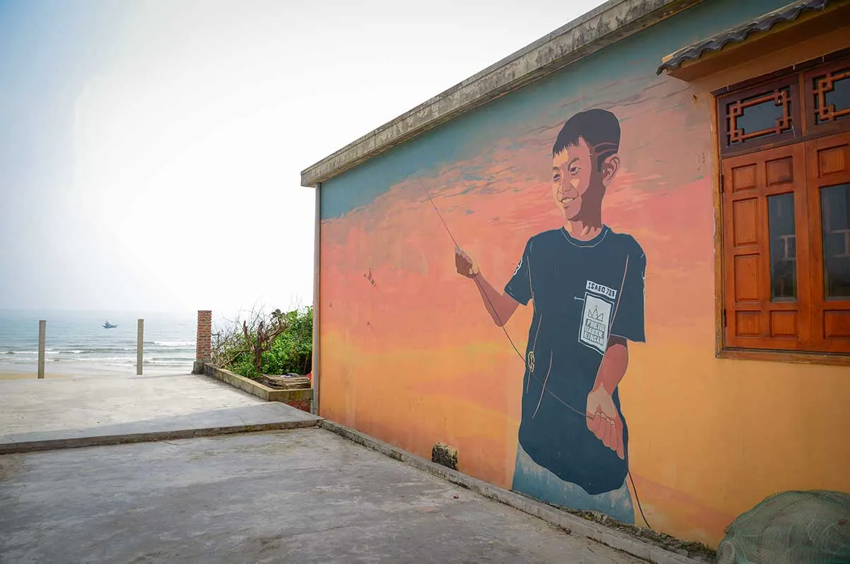 Mural of a boy flying a kite on a beachfront wall in Tam Thanh village.