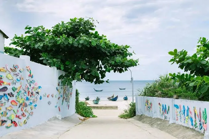 Path with fish art leading to the sea in Tam Thanh Mural Village.