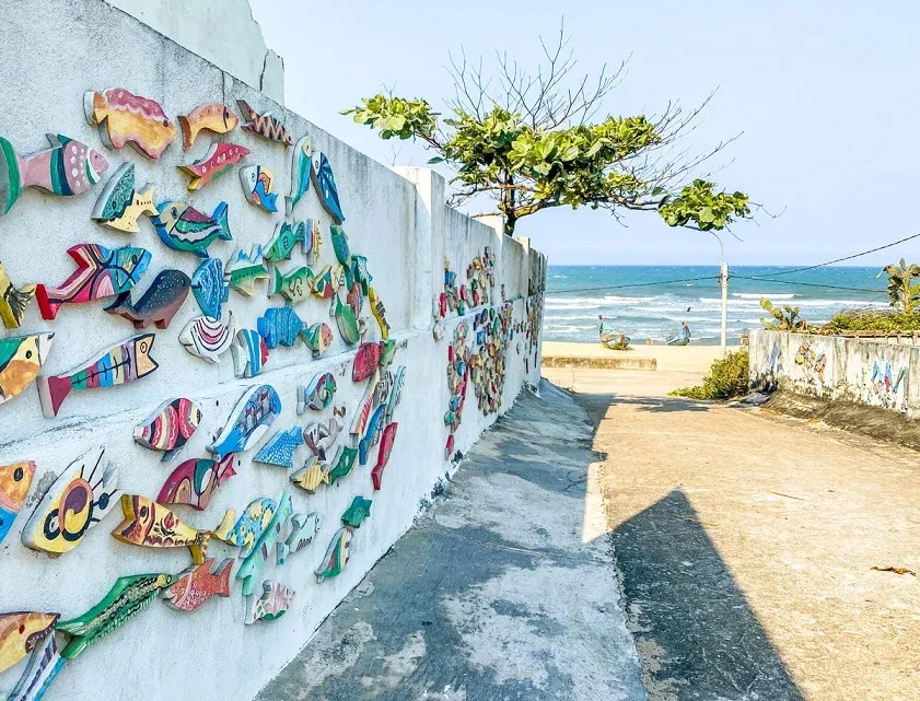Colorful fish decorations on a path to the beach in Tam Thanh Mural Village.
