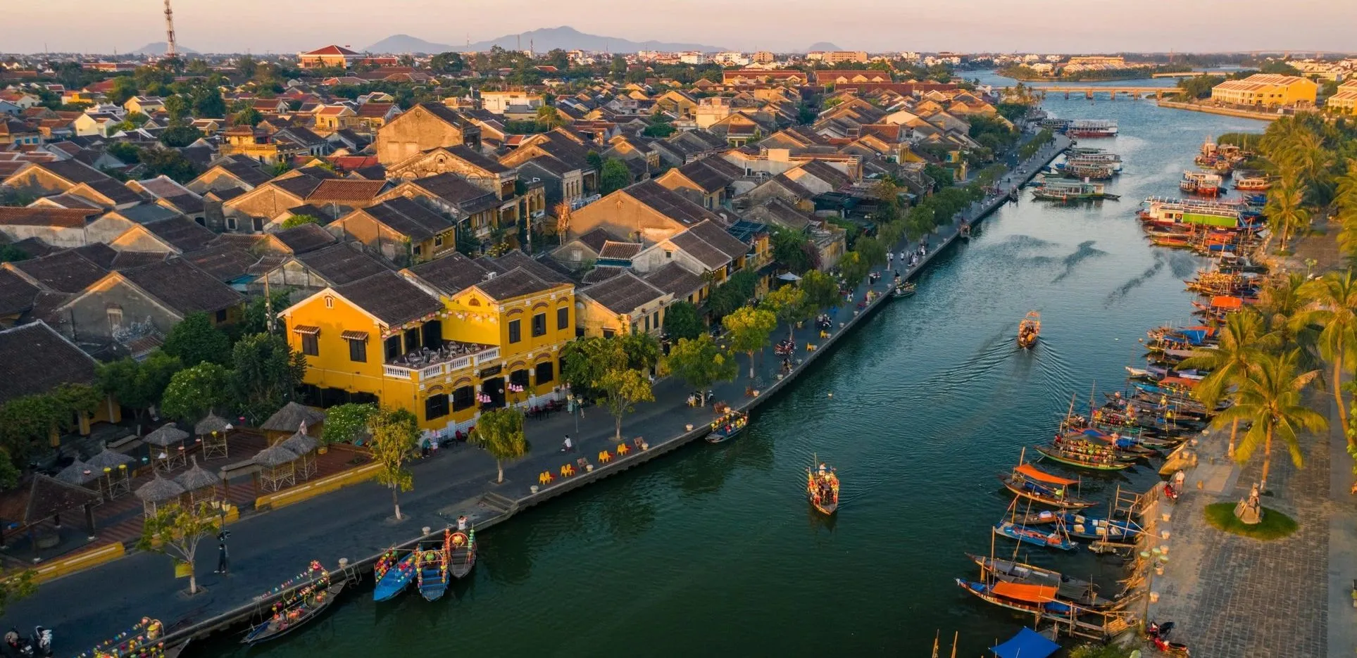 Aerial view of historic yellow buildings and boats on the Thu Bon River Hoi An.