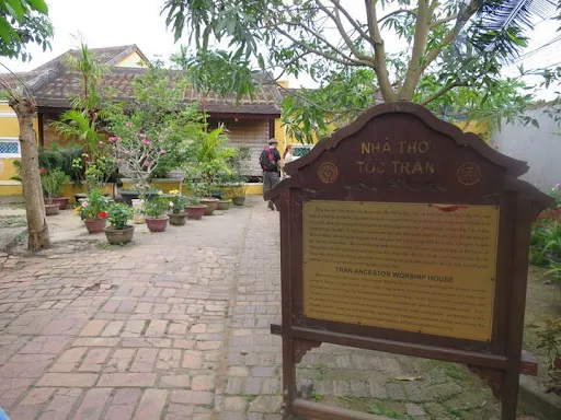 Wooden sign in a brick courtyard with potted plants at tran family chapel